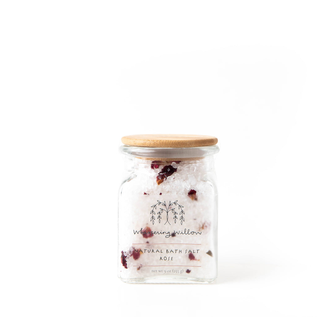Clear glass jar of white salt with rose petals interspersed.