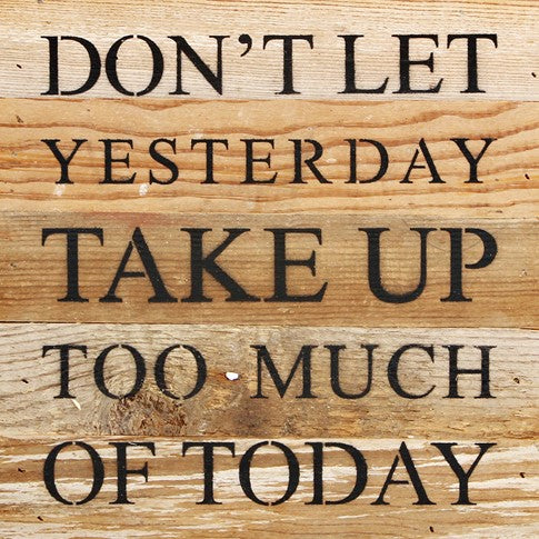 Image shows a natural wood sign. Text reads "Don't let yesterday take up too much of today."