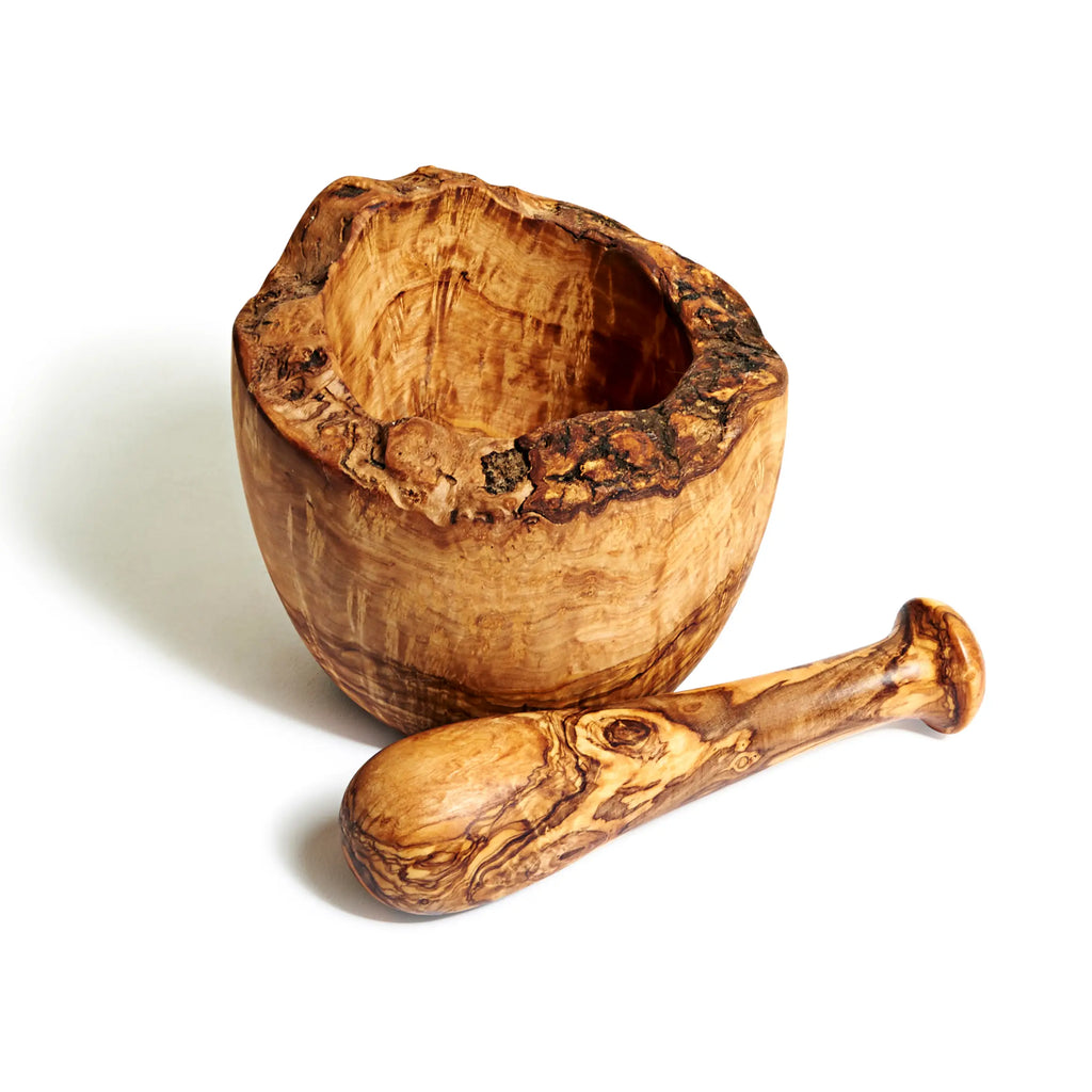 Image of an olive wood mortar and pestle. Image highlights the natural edge of the lip of the bowl.