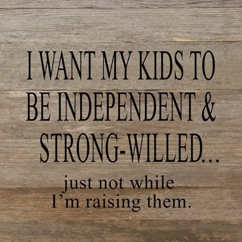 Image shows a natural wood sign. Text reads "I want my kids to be independent and strong-willed...just not while I'm raising them."