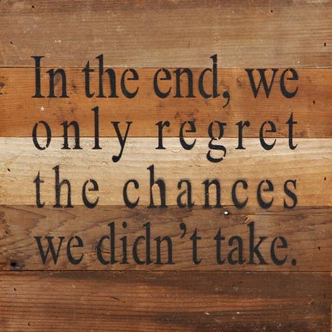 Image shows a natural wood sign. Text reads "In the end, we only regret the chances we didn't take."