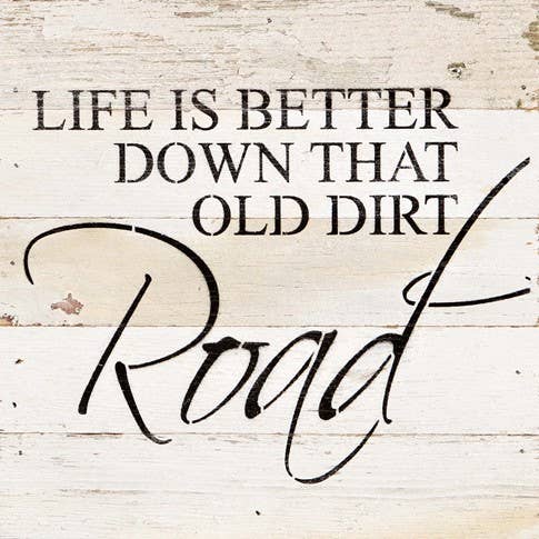 Image shows a natural wood sign. Text reads "life is better down that old dirt road."