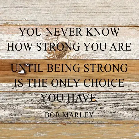 Image shows a natural wood sign. Text reads "You never know how strong you are until being strong is the only choice you have - Bob Marley"