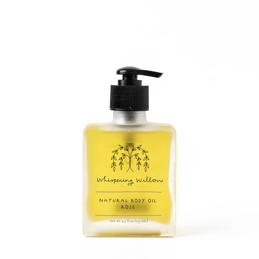 Image shows a clear, square bottle of yellow body oil on a white background.
